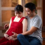 お腹の赤ちゃんえお笑顔で見つめる夫婦