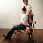 妊婦が椅子に座って、後ろに立つ夫